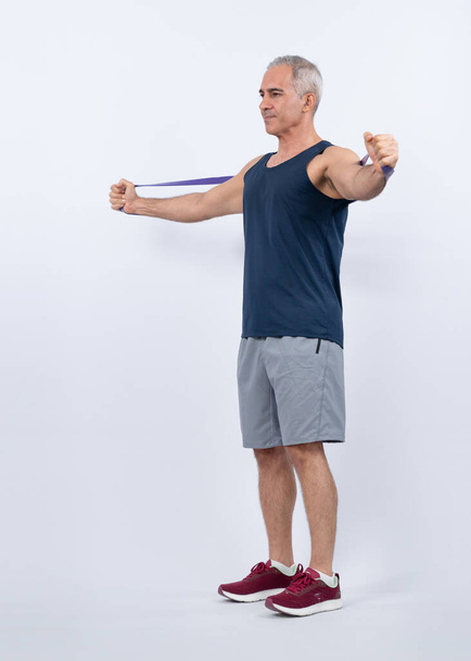 Full body length shot athletic and sporty senior man with fitness resistance band on isolated background. Healthy active physique and body care lifestyle after retirement. Clout - Foto, Imagen