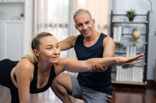 Glückliches aktives Seniorenpaar in Sportkleidung unterstützt und hilft bei der Yoga-Haltung gemeinsam zu Hause. Gesunder Lebensstil für Senioren und Frauen mit Yoga-Übungen. Schlagkraft - Foto, Bild