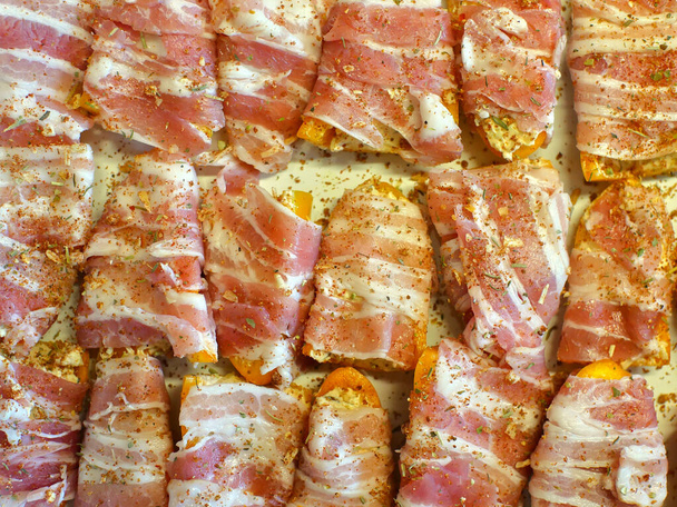 Preparation of Sweet pepper poppers: mini yellow peppers stuffed with cheese and sopasco spice, then rolled in smoked bacon. - Photo, Image