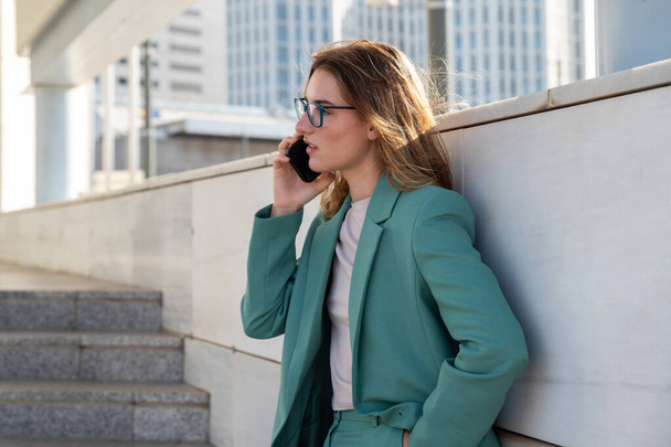 Ділова жінка стоїть на сходах зовні офісної будівлі під час розмови на мобільному телефоні  - Фото, зображення