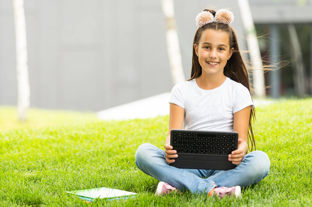 Cute little girl tablet PC in the park. - Foto, Imagem