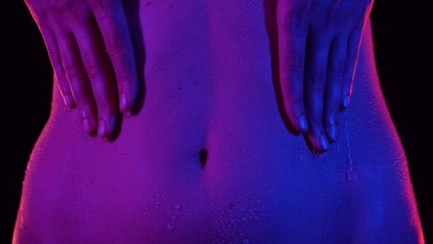 Skin texture and bodycare concept. Portrait of attractive young female model. Closeup shot of beautiful caucasian woman body part in neon light, touching belly area skin in waterdrops after bathing. - Fotografie, Obrázek