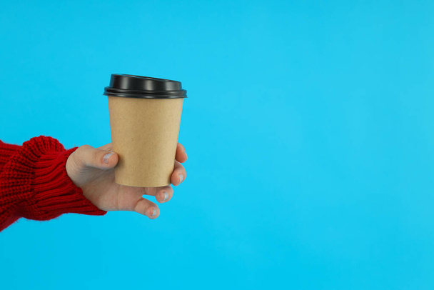 Coffee in a paper cup in hands. on a blue background. - Photo, Image