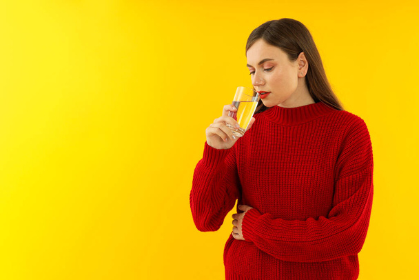 Exhausted girl in a red sweater on a yellow background. - Photo, Image