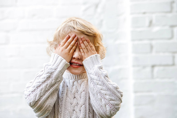 Una ragazza di quattro anni si copre gli occhi con le mani in un simpatico g giocoso - Foto, immagini