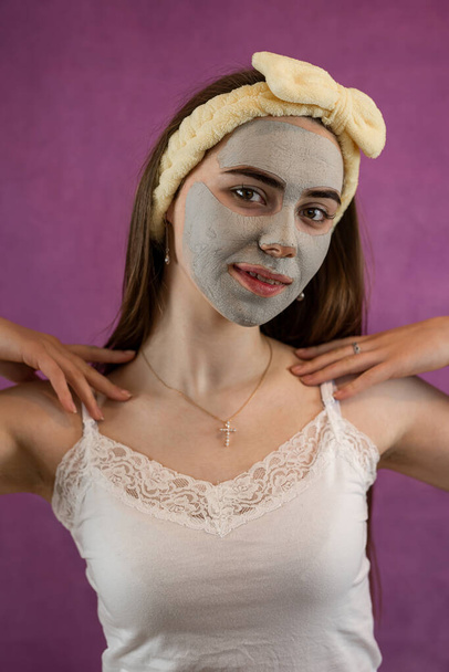 Mulher bonita com máscara facial de barro verde terapêutico isolado em roxo. Spa anti envelhecimento tratamento - Foto, Imagem