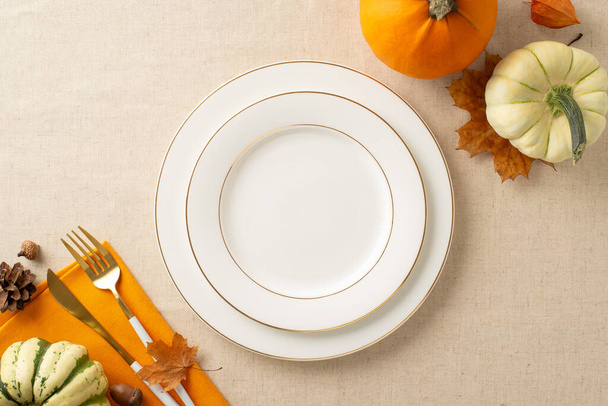Thanksgiving feest arrangement: Bovenaanzicht shot van borden, servet en bestek op een beige tafelkleed versierd met pompoenen, gebladerte, en dennenappel. Delicate herfstvibes nodigen je tekst of bericht uit - Foto, afbeelding