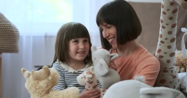 In een verrukkelijke scène in de kinderkamer spelen een blanke moeder en haar dochter fantasierijk met zacht speelgoed. Hun gedeelde lach en creativiteit vullen de ruimte met warmte. - Video