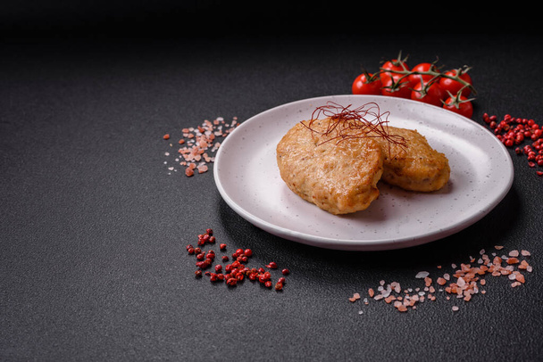 Köstliche gebratene Schnitzel oder Frikadellen mit Salz, Gewürzen und Kräutern auf dunklem Betongrund - Foto, Bild