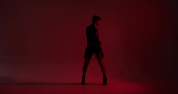 La silhouette captivante d'un danseur caucasien se déplace gracieusement dans la lumière rouge enchanteresse. Leur danse, soulignée par la lueur chaude, crée une expérience visuellement fascinante et évocatrice. - Séquence, vidéo