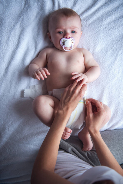 Giovane mamma sta cambiando il suo pannolino bambino carino
 - Foto, immagini