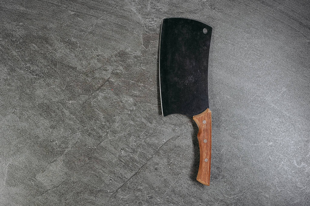 A large professional ax knife with a wooden handle on a stone kitchen table in a professional kitchen - Photo, Image