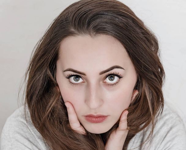 Visage féminin aux grands yeux et aux cheveux foncés. Calme expression faciale close-up - Photo, image