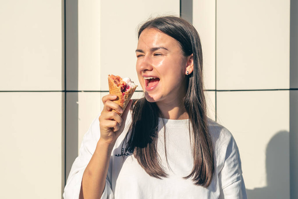 Счастливая молодая женщина с вкусным мороженым в конусе под открытым небом. - Фото, изображение