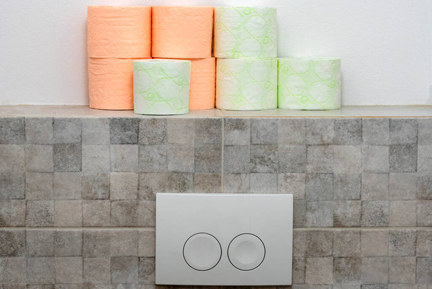 Rotoli di carta igienica e pulsante WC. Rotoli di due colori. Righe di bobine di servizi igienici vicino. Concetto di igiene - Foto, immagini