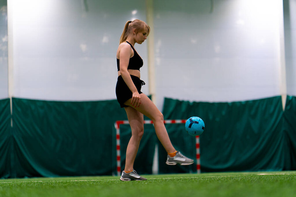 jong meisje is training op het voetbalveld schoppen de bal gooien in de lucht verbetering van haar sport vaardigheden - Foto, afbeelding