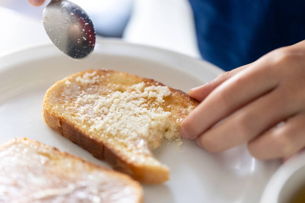 Een vrouw strooit een stuk brood met geraspte kaas, een heerlijk ontbijt. - Foto, afbeelding