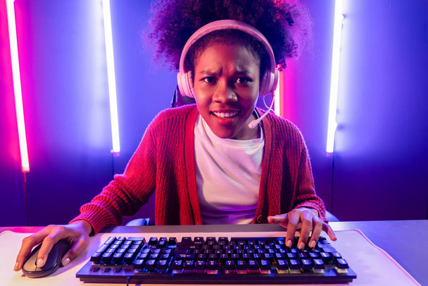 Gaming streamer, Afrikkalainen tyttö pelaa verkossa taistelevat Esport ammattitaitoinen joukkue yllään kuulokkeet neon väri valaistus huone. Puhuminen muut pelaajat höyläys strategioita voittaa kilpailijoita. Maustevalmistaja. - Valokuva, kuva