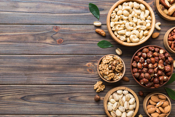 mixed nuts in wooden bowl. Mix of various nuts on colored background. pistachios, cashews, walnuts, hazelnuts, peanuts and brazil nuts. - Photo, Image