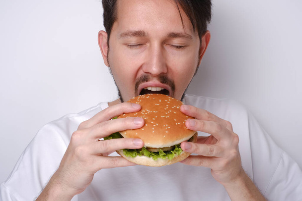 Портрет белого человека, поедающего бургер на белом фоне - Фото, изображение