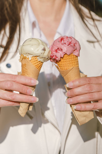 Dos cuernos coloridos de delicioso cono de helado en las manos de una chica. - Foto, imagen
