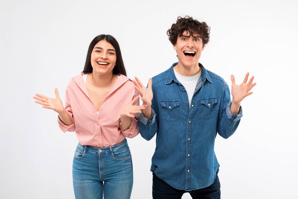 Wow Offer. Excited Young Couple Shouting In Excitement Holding Hands Near Faces On White Studio Background. Emotional Boyfriend And Girlfriend Rejoicing Over Amazing News Looking At Camera - Fotó, kép