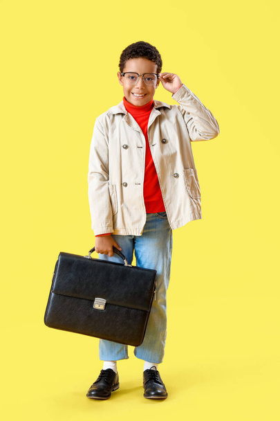 Niño afroamericano con maletín sobre fondo amarillo - Foto, Imagen