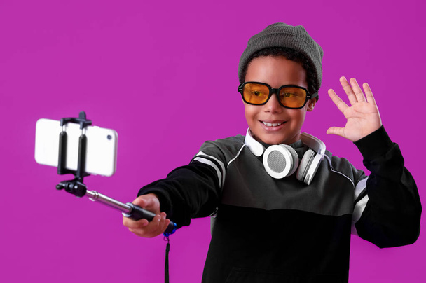 Афро-американский мальчик с мобильным телефоном делает селфи на фиолетовом фоне - Фото, изображение