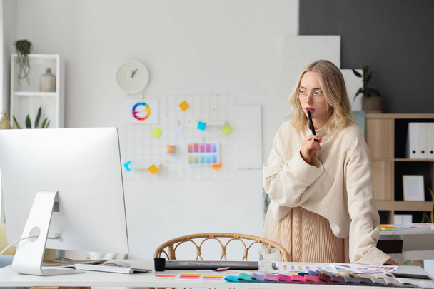 Женщина-дизайнер интерьеров работает с графическим планшетом за столом в офисе - Фото, изображение