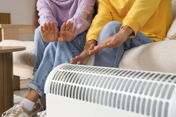 Giovane coppia riscaldamento mani vicino al radiatore a casa, primo piano - Foto, immagini