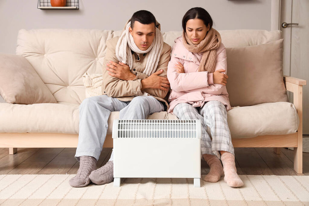 Casal jovem congelado aquecendo perto do radiador em casa - Foto, Imagem