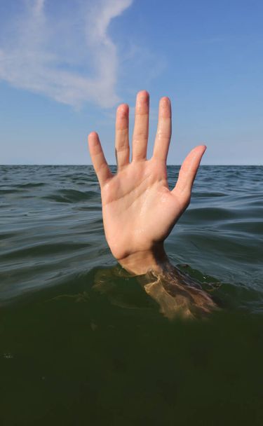 vijf vingers van de hand tijdens het verdrinken in de oceaan en vragen om hulp symbool van falen en falen - Foto, afbeelding