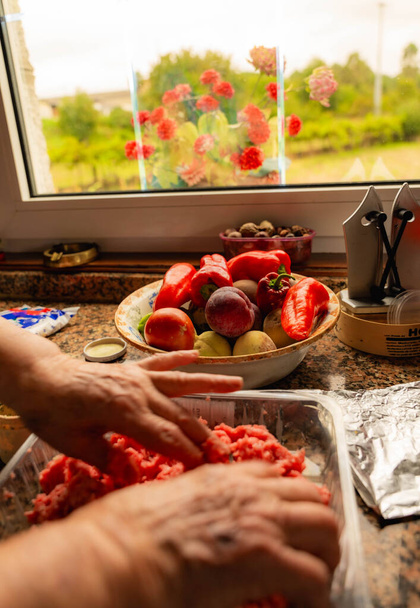 Руки с ножом и пименто, чтобы нарезать последний, который сопровождает лук при приготовлении пищи - Фото, изображение