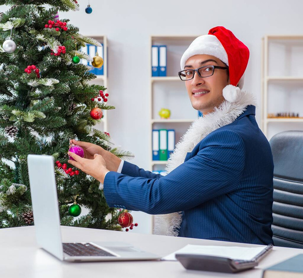 A karácsony ünnepét ünneplő üzletember az irodában. - Fotó, kép