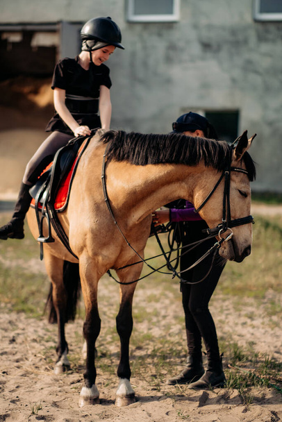 Un adolescente in casco impara a cavalcare in estate, l'istruttore insegna al bambino l'equestrismo.. - Foto, immagini