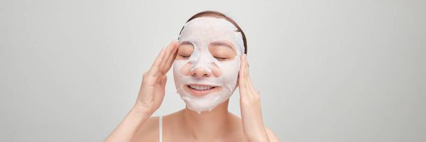 Woman applying sheet mask on her face, on white banner  - Photo, Image