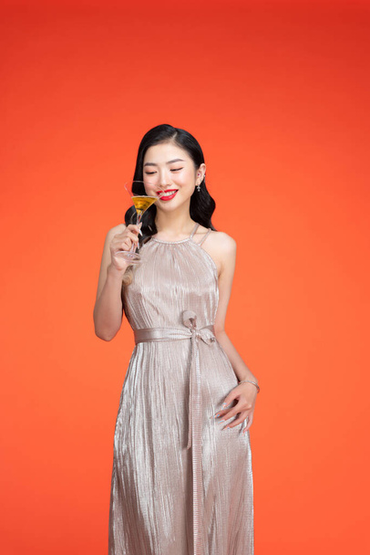 Portrait of attractive young festive asian offering a glass of champagne. - Photo, Image