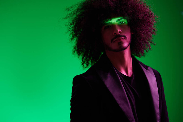 Retrato de um homem elegante em uma jaqueta em um fundo verde multinacional, luz de cor, tendência. Foto de alta qualidade - Foto, Imagem
