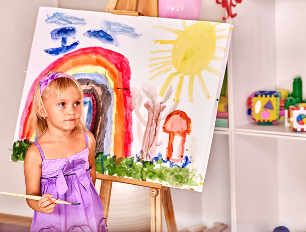 Child painting at easel. - Photo, Image