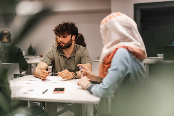 Jeunes entrepreneurs multiculturels discutant d'une nouvelle stratégie pour accroître la productivité au travail lors d'une réunion à table au bureau. - Photo, image