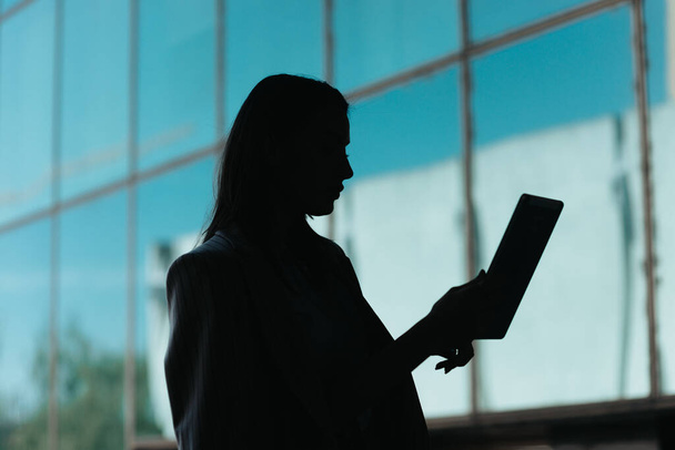 Businesswoman working on tablet in front of big business center, silhouette - Photo, Image