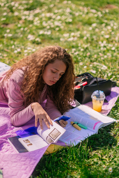 Linda menina de cabelos encaracolados estudando no parque. Ela está usando calculadora - Foto, Imagem