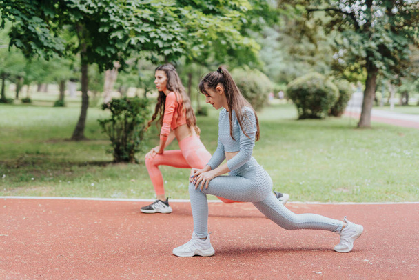 Two active women workout outdoors in an urban park, displaying their fit bodies and sport routine. - Φωτογραφία, εικόνα