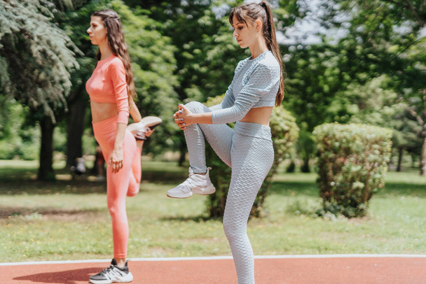 Aktive urbane Sportroutine im Park, zwei fitte, attraktive Frauen dehnen und trainieren gemeinsam und inspirieren zu einem gesunden Lebensstil. - Foto, Bild