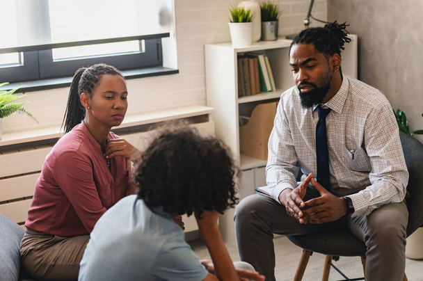 afroamericano hombre psicólogo hablando con madre e hijo en clínica  - Foto, imagen