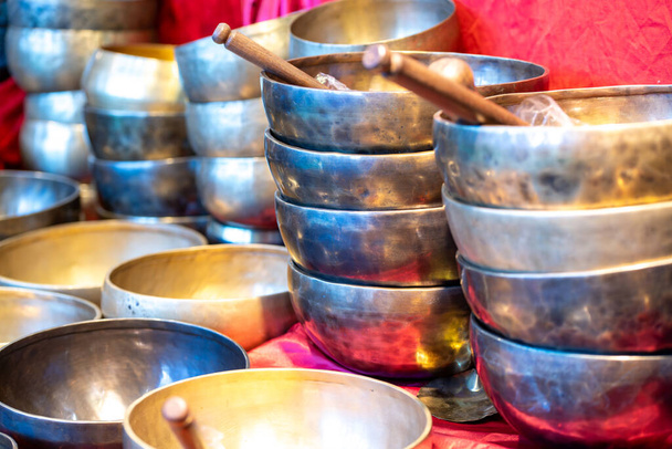 Stacked singing bowls on a red cloth with shining light and partially taps - Photo, Image