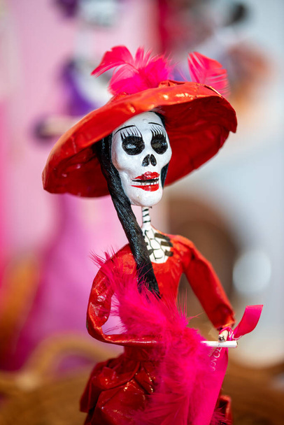 Una piccola figura raffigurante uno scheletro vestito con un vestito rosso e un cappello rosso, simile alle figure del Dias de los muertos - Foto, immagini