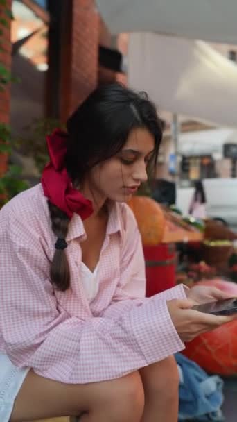 A termelői piac büszkélkedhet egy élénk fiatal nő rózsaszín ruhát, okostelefon készen áll. Kiváló minőségű 4k felvételek - Felvétel, videó