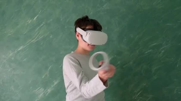 chłopiec bawi się wirtualnym vr słuchawki na zielonym tle - Materiał filmowy, wideo