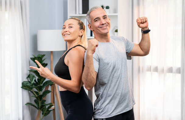 Athletic and sporty senior couple portrait in sportswear with successful or celebrating after overcome struggle posture as home exercise concept with healthy fit body lifestyle after retirement. Clout - Photo, Image